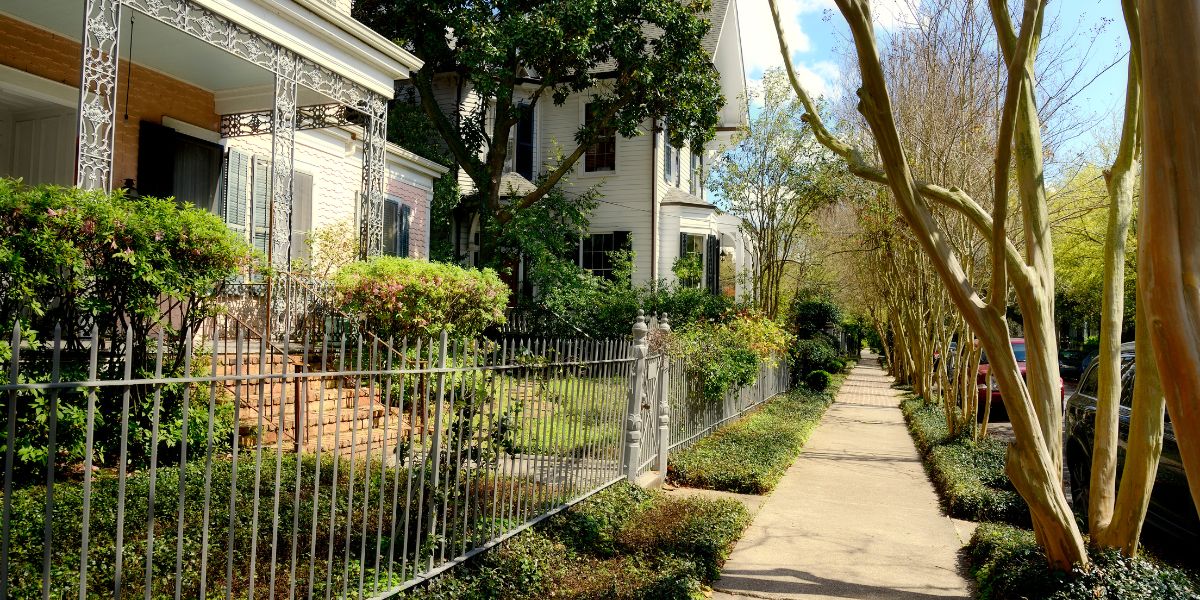 Historic New Orleans home with an iron gate and columns along a brick pathway.
