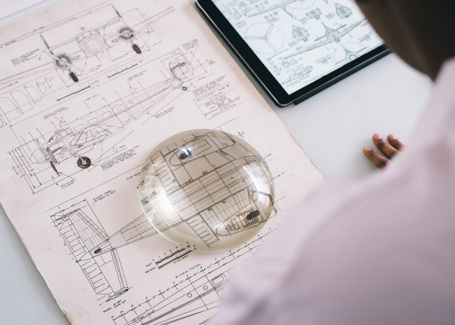 An entrepreneur in a bright, modern office carefully examines the fine details of a blueprint with a magnifying glass, signifying scrutiny of standard agreements.