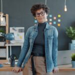 Professional person sits at a sleek, modern desk with their head in their hands, looking stressed and overwhelmed by the w...