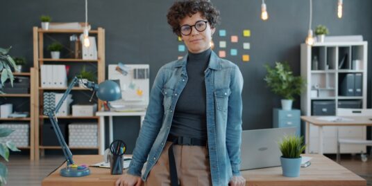 Professional person sits at a sleek, modern desk with their head in their hands, looking stressed and overwhelmed by the w...